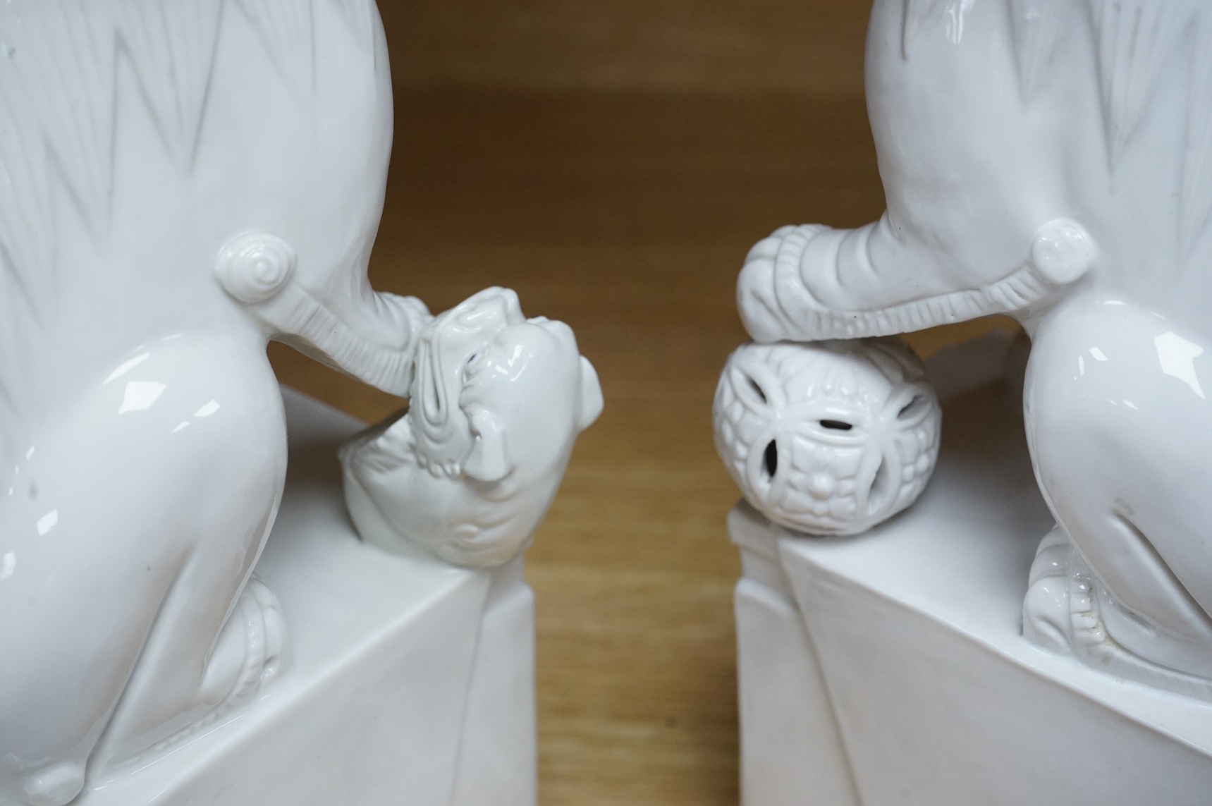 A pair of Chinese white glazed lion dogs, stamped ‘Wai Ming Hong Kong’ to base, 30cm